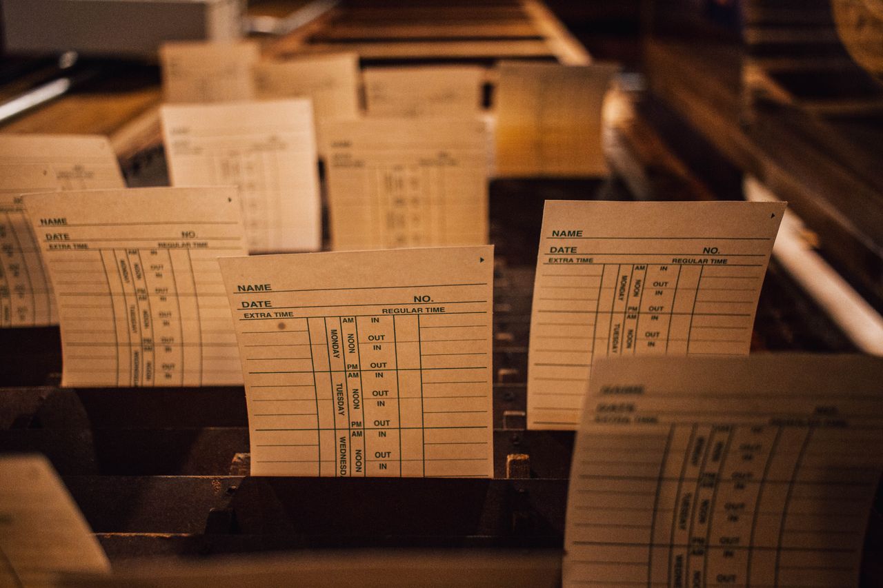 Close-up of vintage time cards in a wooden filing system, showcasing retro workplace documentation.